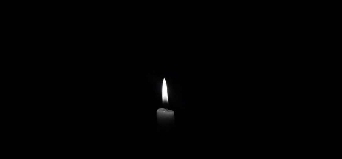 A dark black photo with a faint candle making little light.